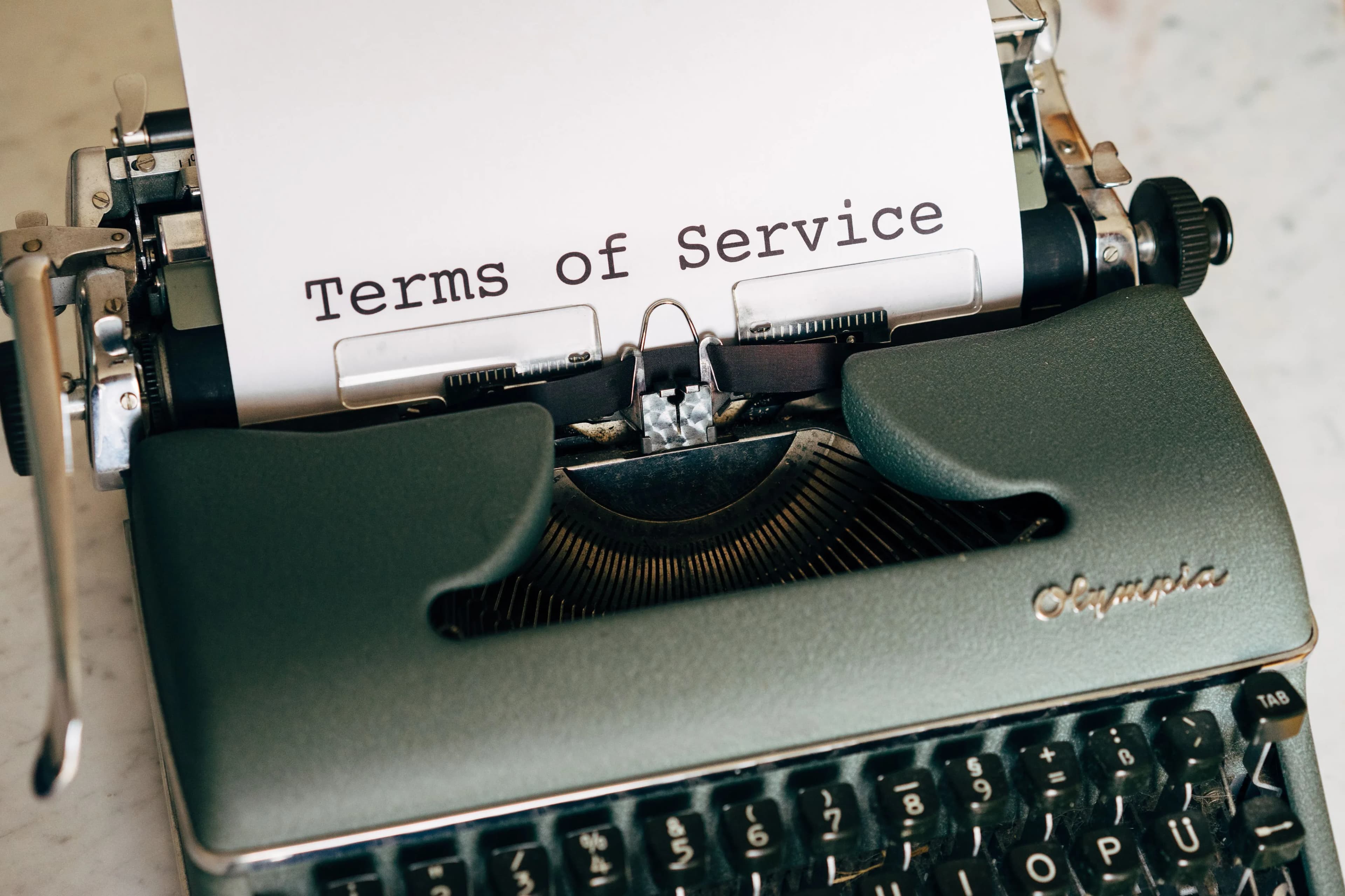 A vintage typewriter printing a sheet of paper that reads Terms of Service